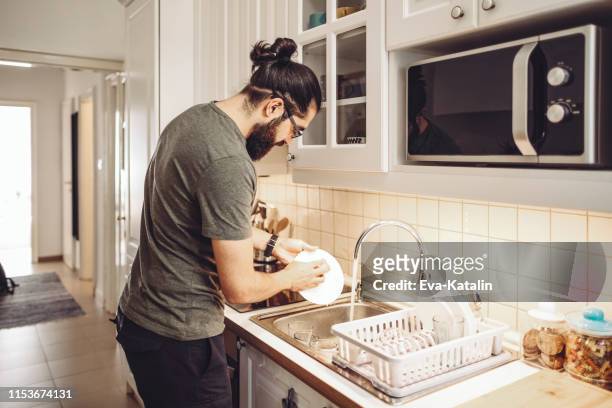 ung man tvätta rätter hemma - washing dishes bildbanksfoton och bilder