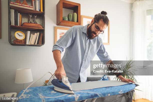 junger mann bügelt sein hemd - ironing stock-fotos und bilder