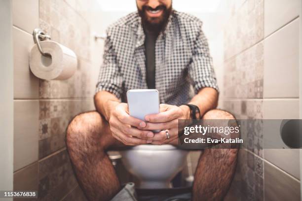 man using a smart phone while sitting on the toilet - men taking a dump stock pictures, royalty-free photos & images