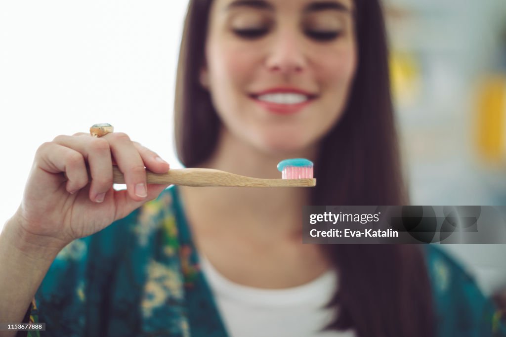 At home - young woman brushing her teeth