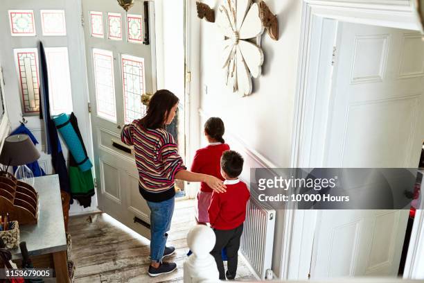 mother opening front door for two school children - abrir a porta sair imagens e fotografias de stock
