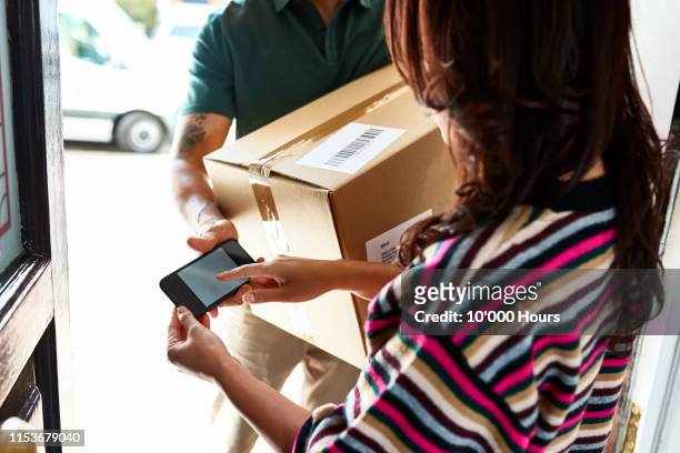 woman using electronic device to sign for parcel - digital signature stock-fotos und bilder
