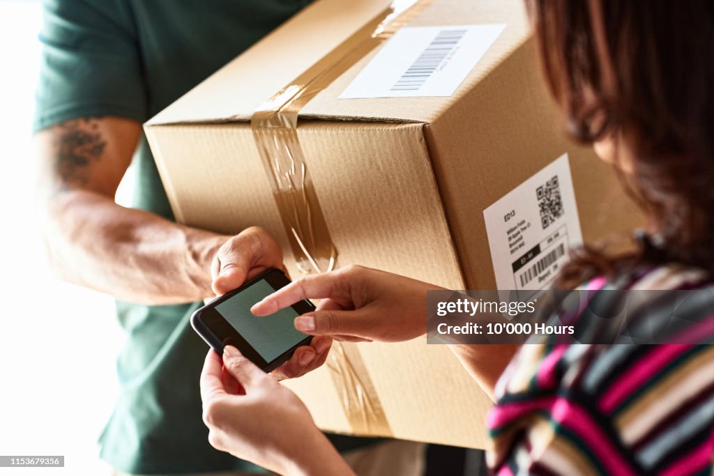 Woman using smartphone to sign for parcel delivery