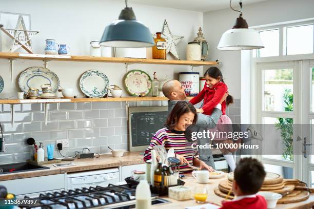 father lifting daughter and smiling as mother makes breakfast - vietnamese food stock-fotos und bilder