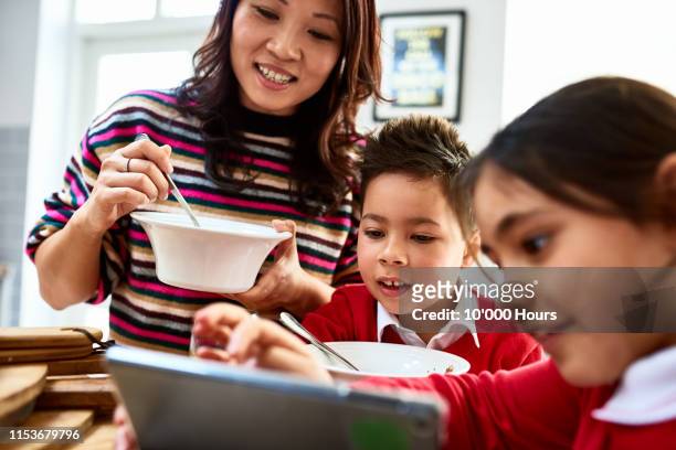single mother eating bowl of cereal and watching children online - filipino family eating fotografías e imágenes de stock