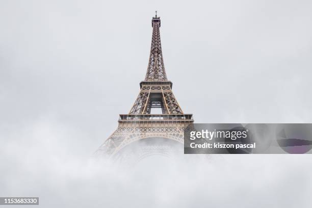eiffel tower in paris disappearing in the fog . french culture . - monuments paris stock-fotos und bilder