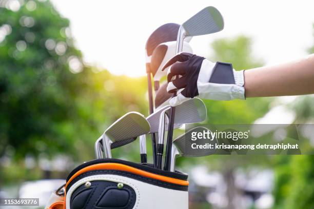 golf concept. hand man removing a golf club from his golf bag to start playing professional golf over green course. - golf tournament stock pictures, royalty-free photos & images