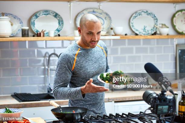 mature man holding vegetarian food and talking to video camera - cooking on camera stock-fotos und bilder