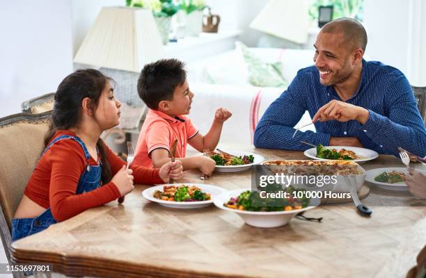 cheerful father smiling and talking with family at meal time - filipino family dinner stock-fotos und bilder