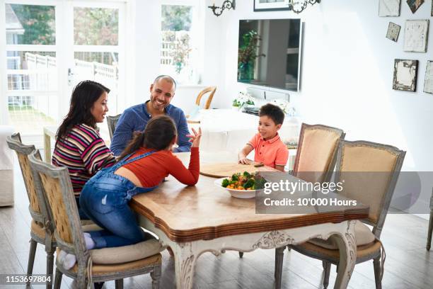 family with two children sitting at dinner table and talking - filipino family dinner fotografías e imágenes de stock