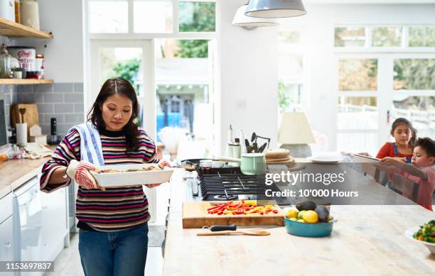 woman holding hot casserole dish in kitchen - filipino woman stock-fotos und bilder