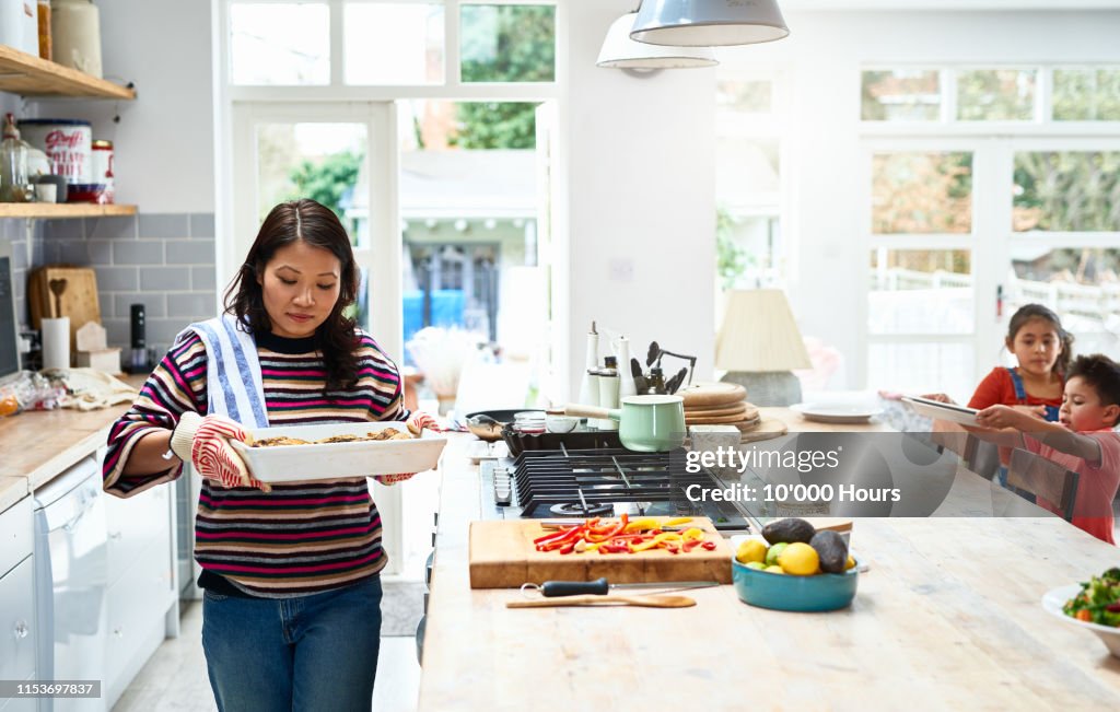 Woman holding hot casserole dish in kitchen