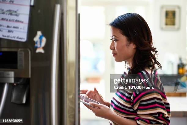 mid adult woman ordering food shopping on digital tablet - vietnamese ethnicity stock pictures, royalty-free photos & images