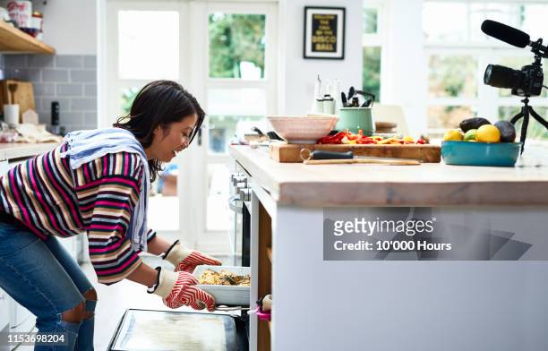 woman taking home baked meal out of oven - woman back stock-fotos und bilder