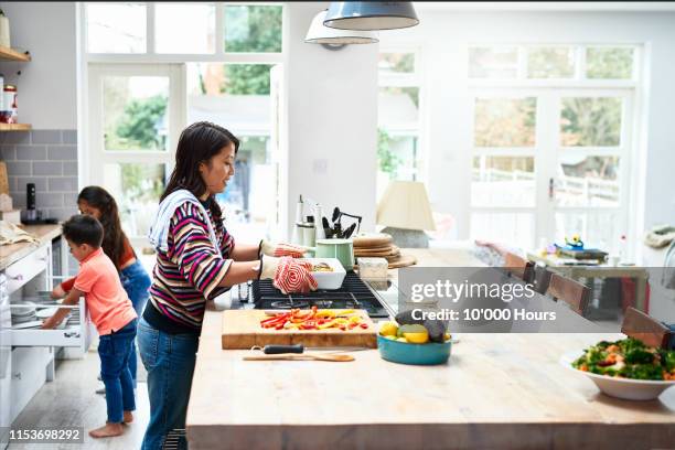 woman placing fresh home made food on kitchen counter - asian family cooking stock pictures, royalty-free photos & images