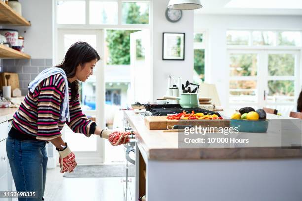 woman adjusting oven and preparing dinner in kitchen - hot vietnamese women stock pictures, royalty-free photos & images