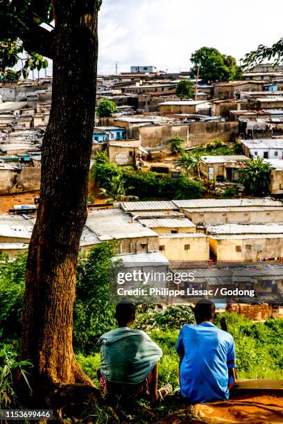 teenagers sitting over slums in abidjan, ivory coast. - ivory coast town bildbanksfoton och bilder