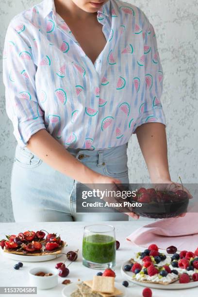 eating healthy breakfast. toasts with seasonal berries in woman' s hands. clean eating, dieting, detox, vegetarian food concept - body detox stock pictures, royalty-free photos & images