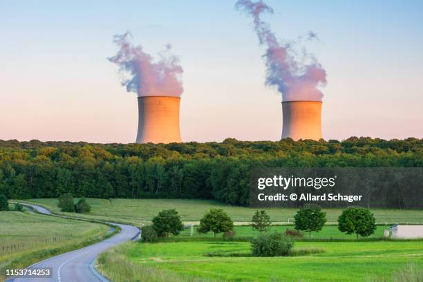 steaming cooling towers at nuclear power plant around sunset - kernenergie stock-fotos und bilder