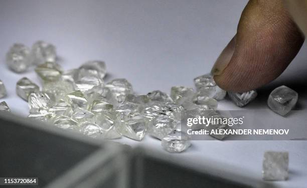 An employee inspects rough diamonds in Alrosa Diamond Sorting Center in the town of Mirny on July 1, 2019. - Russian Alrosa gets its diamonds in the...