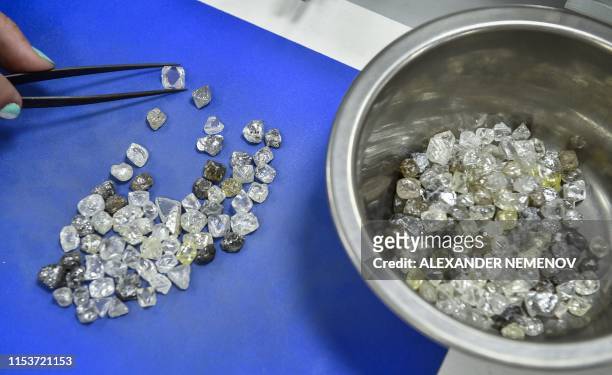 An employee inspects rough diamonds in Alrosa Diamond Sorting Center in the town of Mirny on July 1, 2019. - Russian Alrosa gets its diamonds in the...