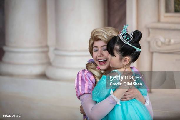 An actress dressed as Rapunzel hugs a young girl at Walt Disney Co.'s Shanghai Disneyland theme park towards the iconic castle during a trial run...