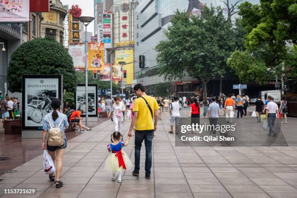 Young girl wearing a Snow White dress walks down Nanjing Road shopping district with her parents in Shanghai, China, on Sunday, July 3, 2016.