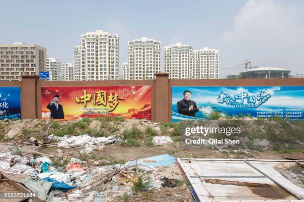 Poster featuring Xi Jinping, China's president, hangs on a wall as residential and commercial buildings stand in the background at the Caofeidian...