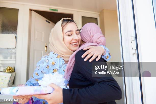 young woman welcomes a friend to her birthday celebration - eid fitr stock-fotos und bilder