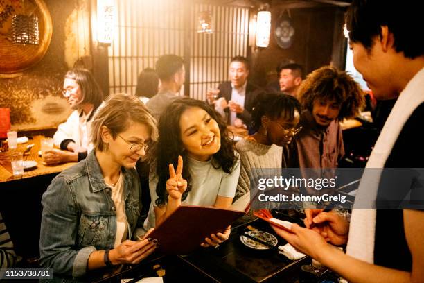 candid portrait of young women ordering food in restaurant - crowded restaurant stock pictures, royalty-free photos & images