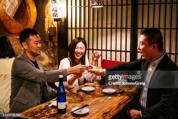 portrait of japanese friends celebrating together with saki - sake stock pictures, royalty-free photos & images
