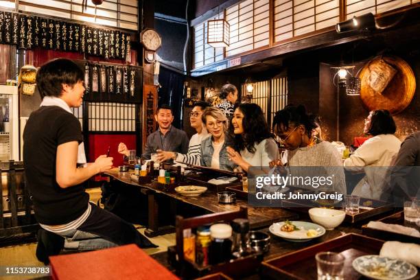 grupo de amigos pidiendo comida en japonés izakaya - izakaya fotografías e imágenes de stock