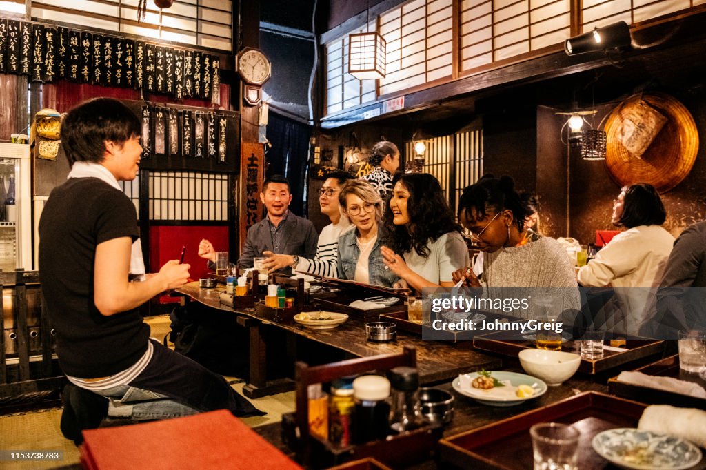 Groep vrienden het bestellen van voedsel in het Japans Izakaya