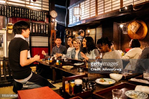 group of friends ordering food in japanese izakaya - japonês imagens e fotografias de stock