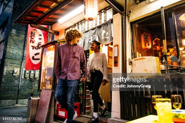 attraktives junges ehepaar, das das restaurant verlässt, hält die hände - tokyo travel destinations stock-fotos und bilder