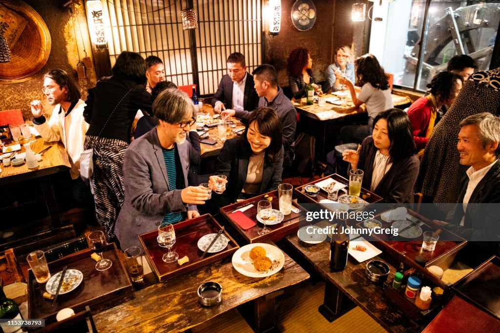 Work friends toasting each other in Japanese Izakaya