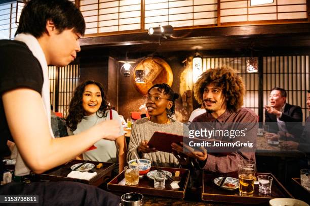 waiter taking food order from friends in japanese restaurant - japanese restaurant stock pictures, royalty-free photos & images