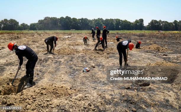 Members of the Raqa Civil Council 's first responders team search for human remains at a mass grave site in the Fukheikha agricultural suburb about...