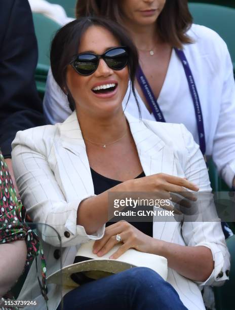 Britain's Meghan, Duchess of Sussex smiles as she watches US player Serena Williams playing against Slovakia's Kaja Juvan during their women's...