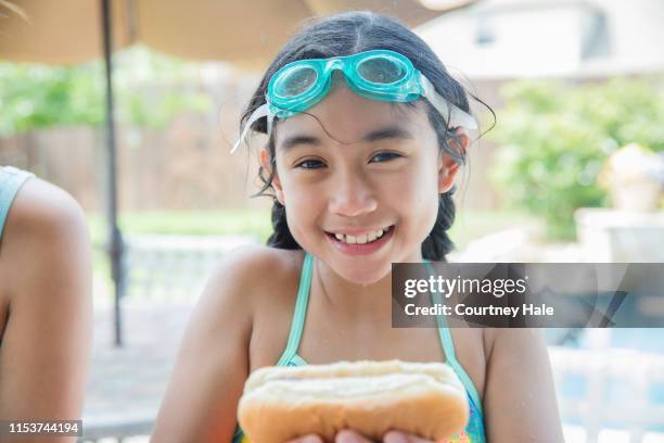 adorable elementary age asian little girl wearing swim goggles and enjoying backyard barbecue - block party stock pictures, royalty-free photos & images