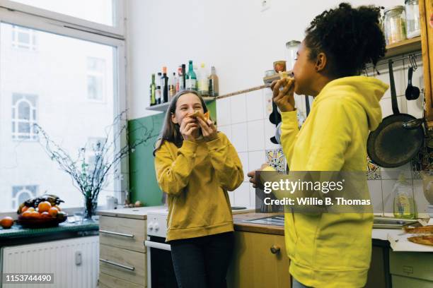 tween girlfriends eating pizza in kitchen - casa sezione foto e immagini stock