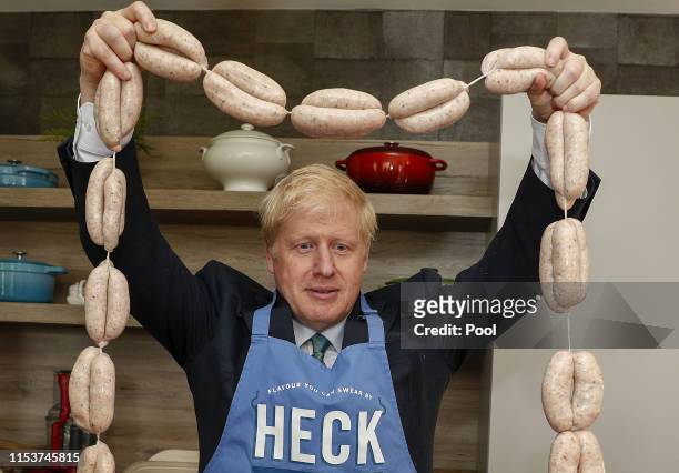 Boris Johnson, former U.K. Foreign secretary, holds up a string of sausages around his neck during a visit to Heck Foods Ltd. Headquarters, as part...