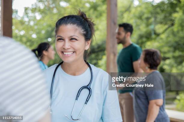 friendly nurse helps patient during an outdoor health fair or free clinic event - film and television screening stock pictures, royalty-free photos & images