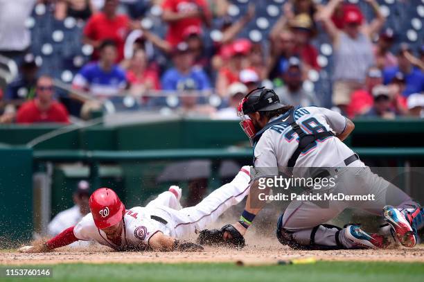 Trea Turner of the Washington Nationals is safe at home plate against Jorge Alfaro of the Miami Marlins on a two run RBI double by Gerardo Parra in...