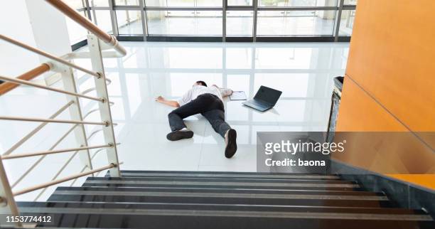 el hombre se desliza cayendo sobre el suelo mojado en un edificio de oficinas moderno. - fainting fotografías e imágenes de stock