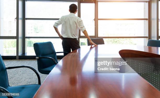 lone business executive looking out of the window in boardroom - office solitude stock pictures, royalty-free photos & images