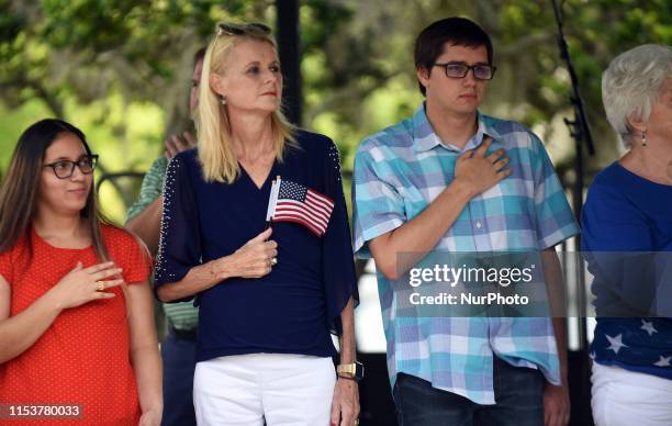 Citizenship candidates stand during the singing of the national anthem during a special naturalization ceremony at the City of Winter Park's 24th...