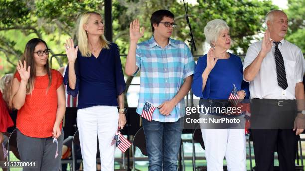 Citizenship candidates hold flags while taking the Oath of Allegiance during a special naturalization ceremony at the City of Winter Park's 24th...