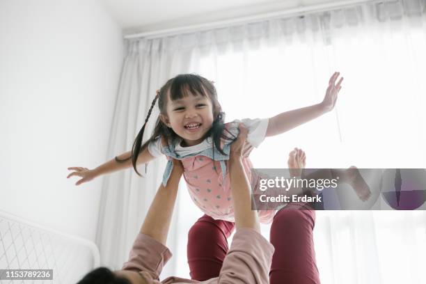 thailändische großmutter und enkelin spielen zusammen auf dem bett-stock image - child strong stock-fotos und bilder