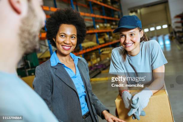 young team manual workers and supervisor standing inside warehouse with package - trabajador manual stock pictures, royalty-free photos & images